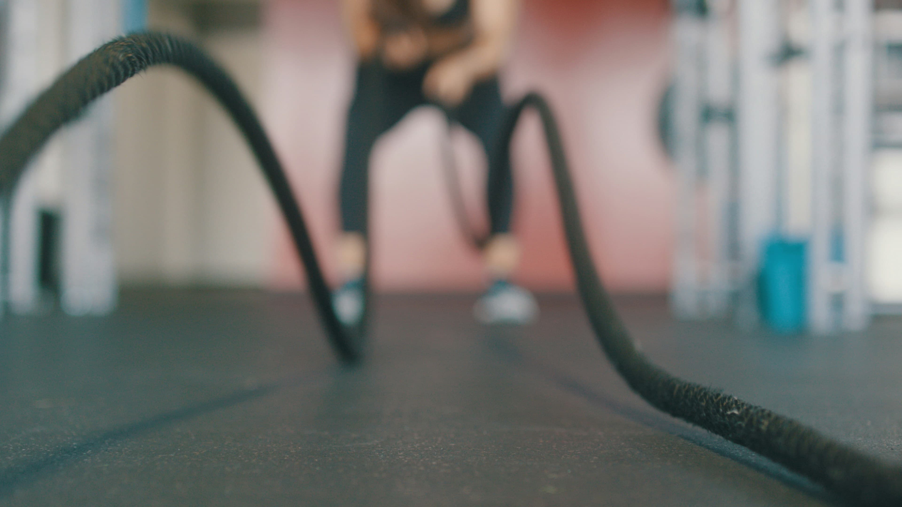 Athlete training with battle ropes in a professional gym, representing sports nutrition supply.